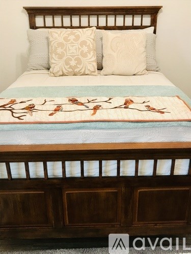A bed with a wooden headboard and a quilt with a bird design on it.