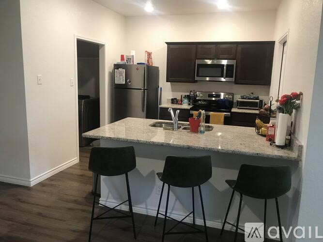 A kitchen with a granite countertop and black bar stools.