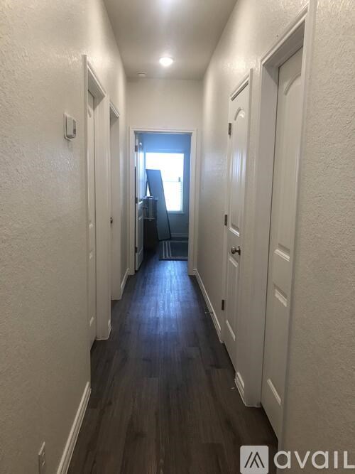 A long hallway with doors on both sides and a light at the end.
