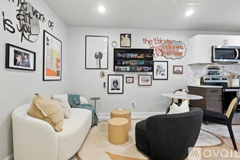 A living room with a white couch, a black chair, and a white coffee table.