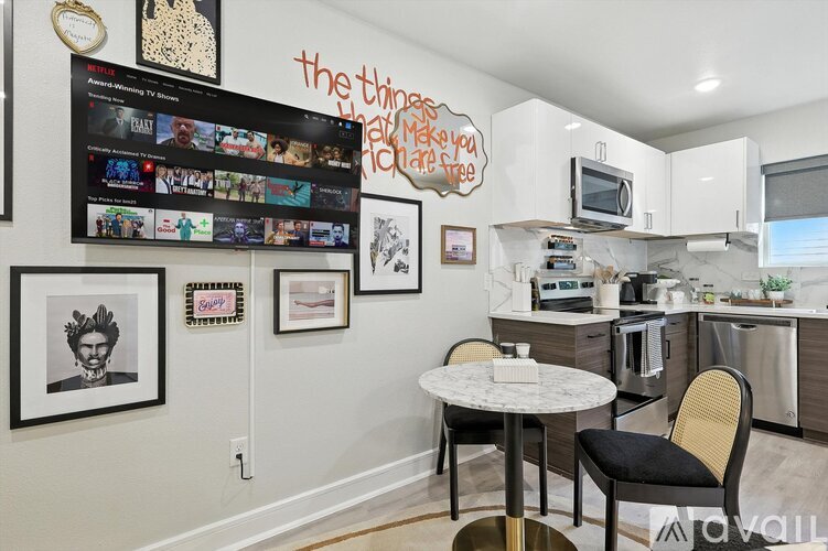 A kitchen with a table and chairs in front of a wall with pictures and a TV.