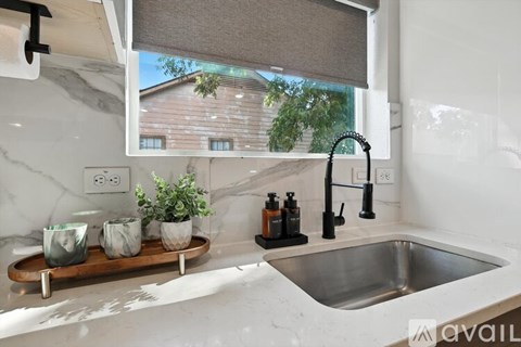 A kitchen with a marble countertop and a stainless steel sink.