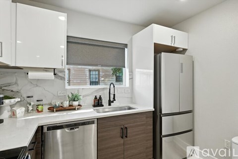 A modern kitchen with a stainless steel dishwasher and white cabinets.