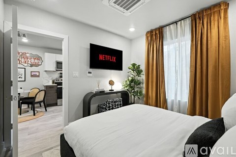 A bedroom with a large bed, a nightstand with a lamp, and a wall with a city skyline mural.