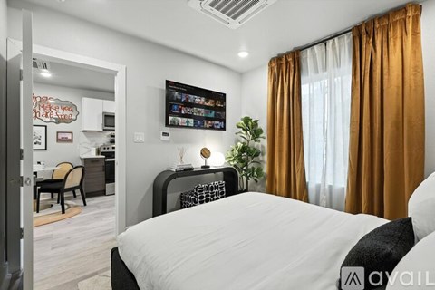 A bedroom with a large bed and a television mounted on the wall.