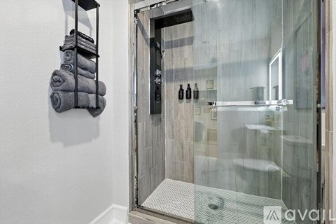 A bathroom with a glass shower door and towel rack.