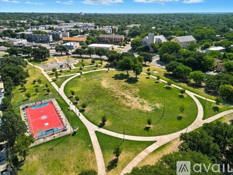 A park with a red track and a white fence.