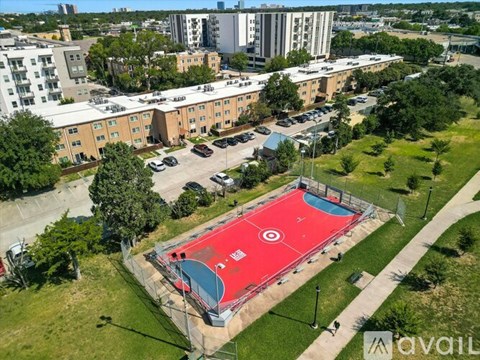 A red basketball court is surrounded by apartment buildings.