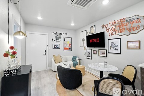 A living room with a white couch, a black chair, a white coffee table, and a wall with pictures and a quote.