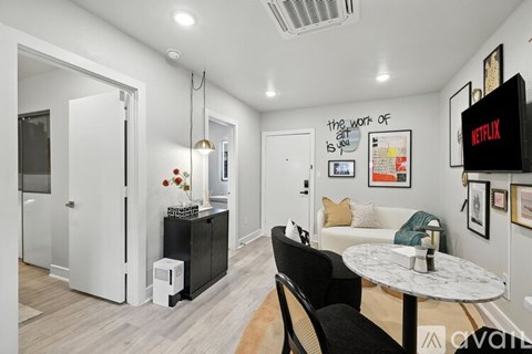 A living room with a white couch, a black chair, and a white coffee table.