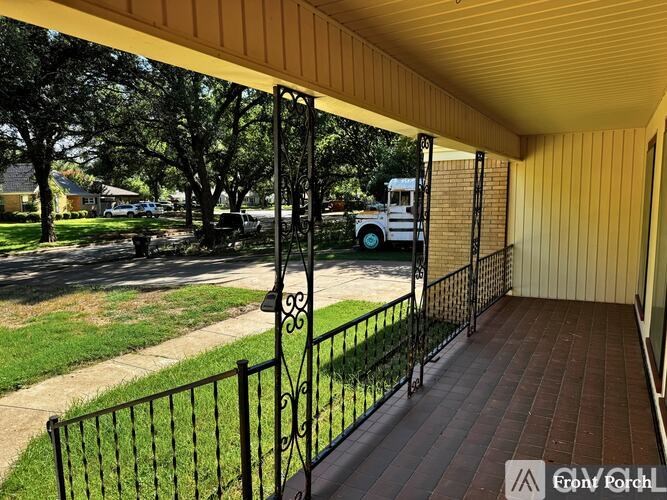 A porch with a black railing and a white van in the background.