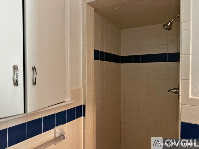 A white bathroom with blue tiles on the bottom.
