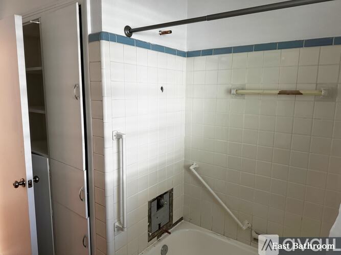 A white tiled bathroom with a walk-in shower and a door.