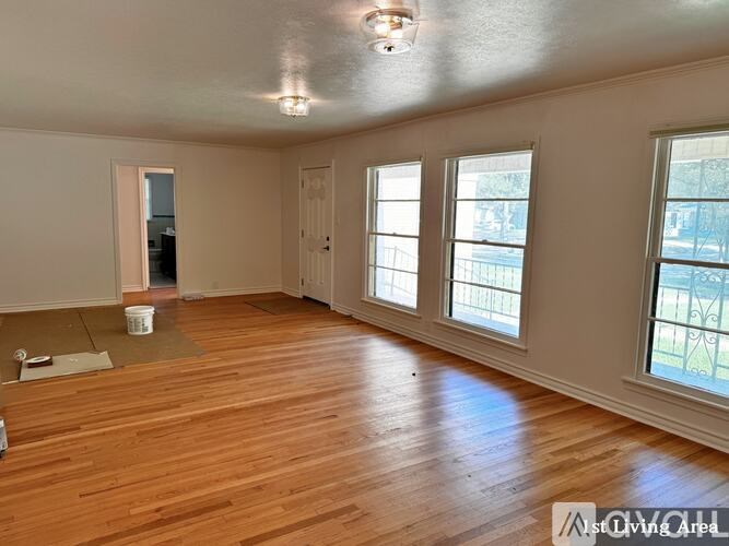 A living area with wood flooring and a window overlooking a fence.