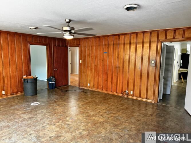 A room with wooden walls and a ceiling fan.