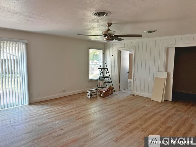 A room with a ceiling fan and wooden flooring.