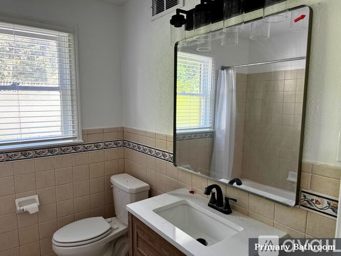 A bathroom with a toilet, sink, and mirror.