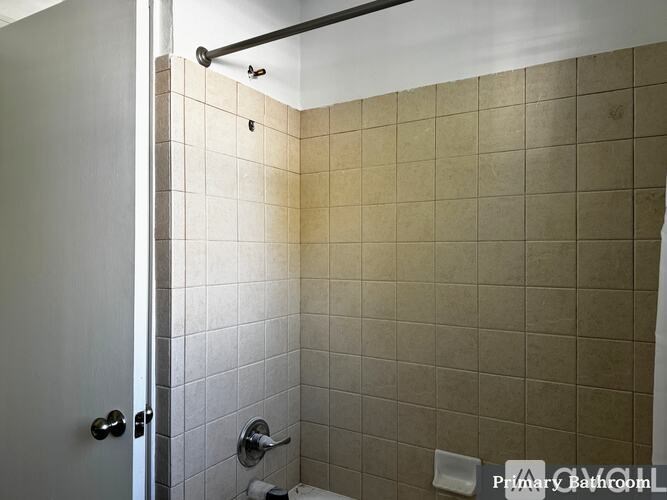 A bathroom with a white door and a tiled wall.