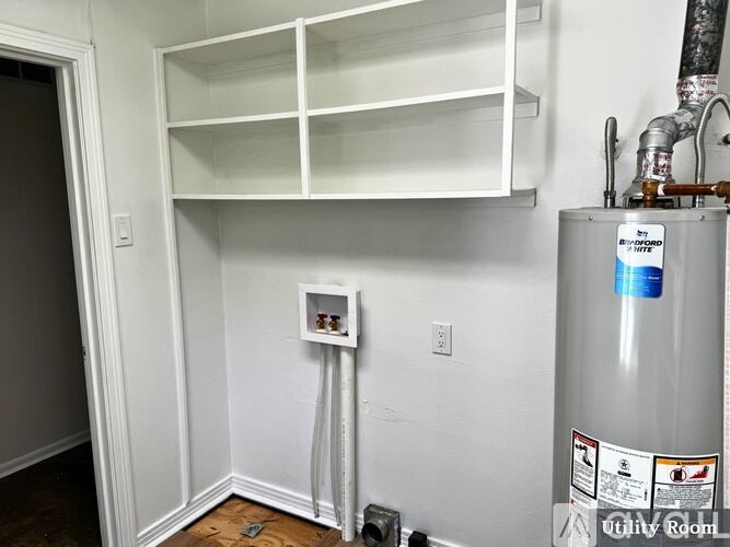 A white shelving unit is mounted above a water heater in a room.
