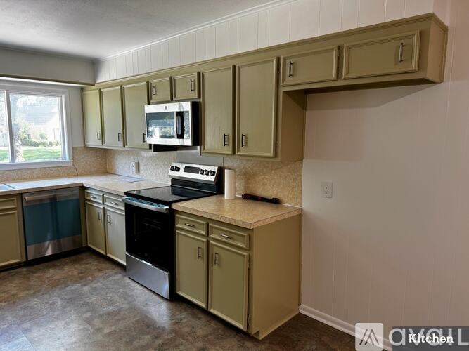 A kitchen with beige cabinets and a granite countertop.