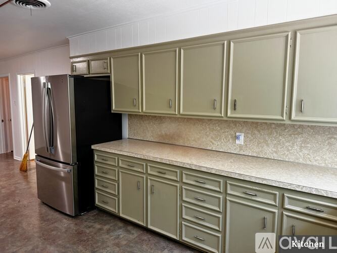 A kitchen with a black fridge and white cabinets.