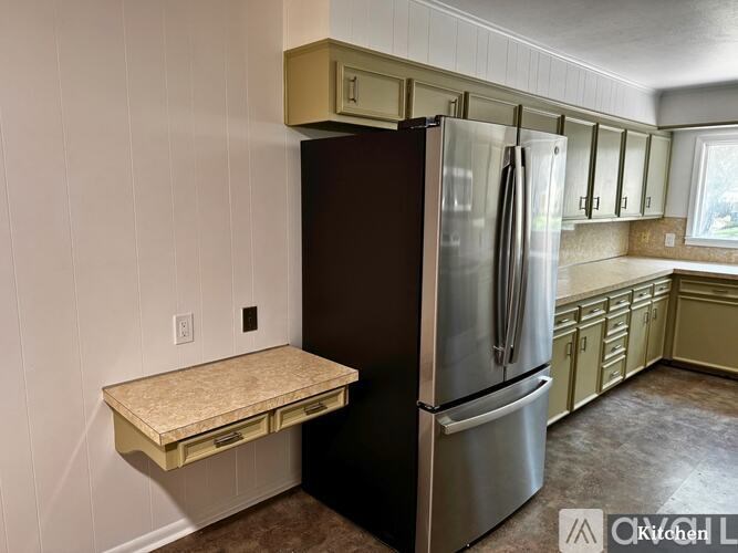 A kitchen with a refrigerator and a countertop.