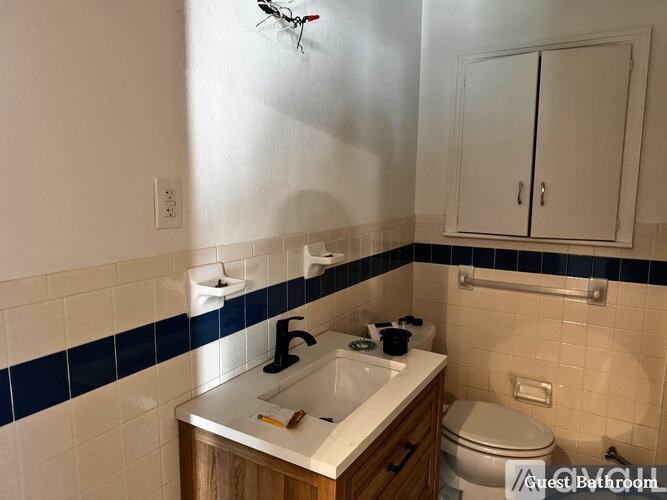 A bathroom with a sink, toilet, and a cabinet.