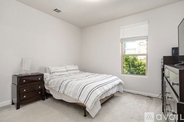 A bedroom with a bed, nightstand, and window.