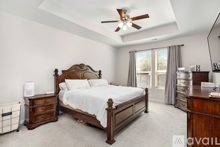 A bedroom with a large bed, a dresser, and a ceiling fan.