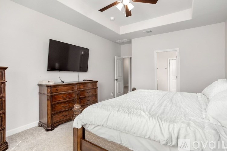 A bedroom with a bed, dresser, and television.