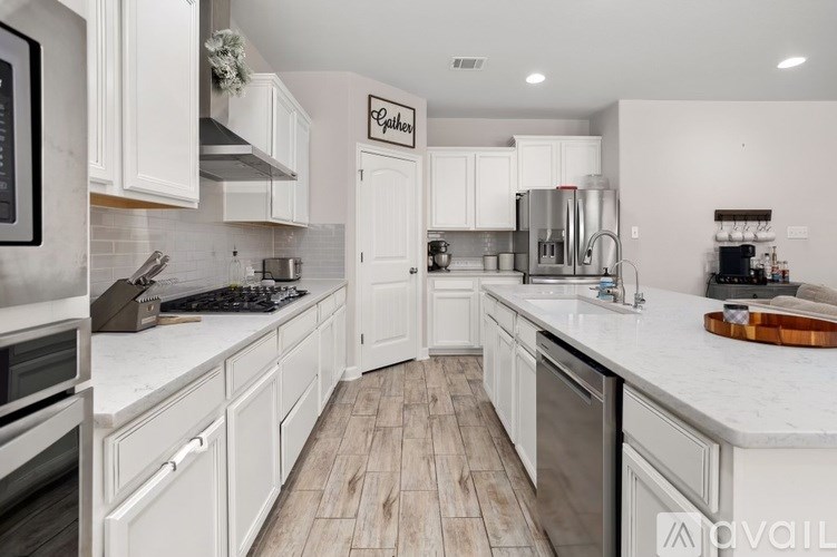 A kitchen with white cabinets and a wooden floor.