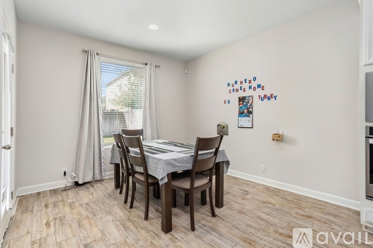 A dining room with a table and chairs and a sign on the wall.