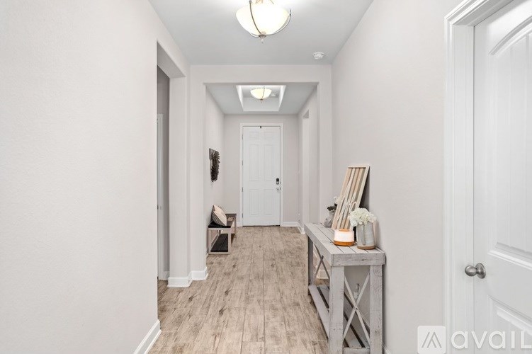 A hallway with a table and chairs on the left and a door on the right.