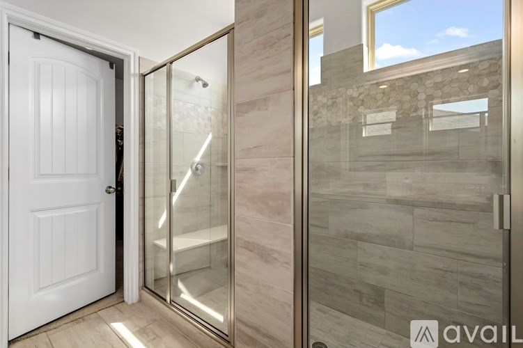 A bathroom with a glass shower door and a white door.