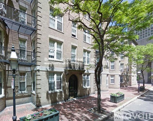 A tree in front of a building with a balcony.
