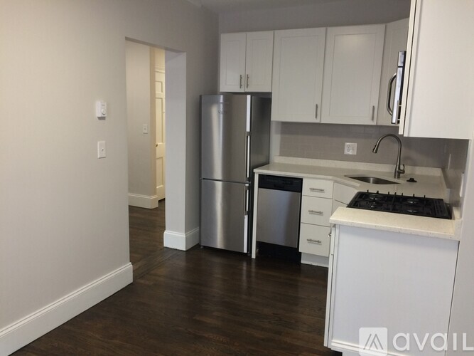 A kitchen with white cabinets and a stainless steel refrigerator.