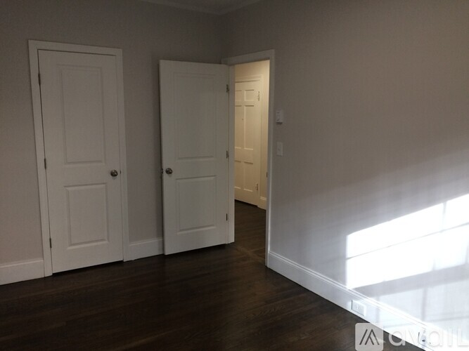 Two white doors in a room with wooden floors.