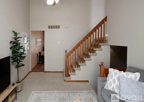 A living room with a grey couch and a wooden staircase.