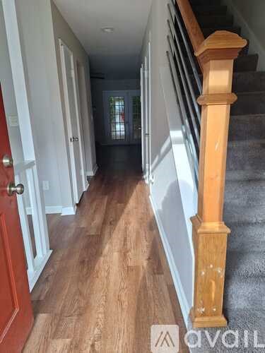 A hallway with a red door and wooden stairs.