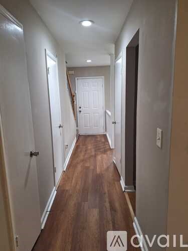 A hallway with wooden floors and white walls.