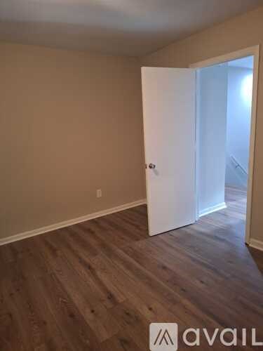 A room with a white door and wooden flooring.