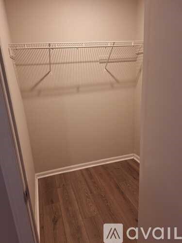 A small, empty closet with a wooden floor and white walls.
