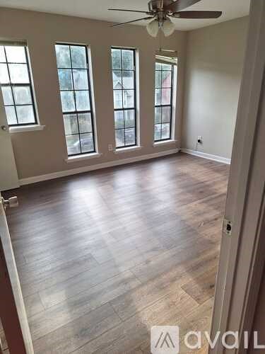 A room with a ceiling fan and wooden flooring.