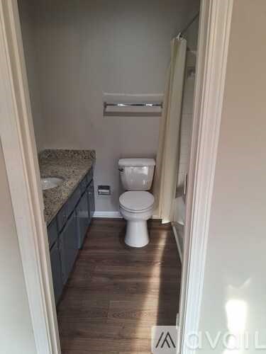 A white toilet sits in a bathroom with a granite countertop.