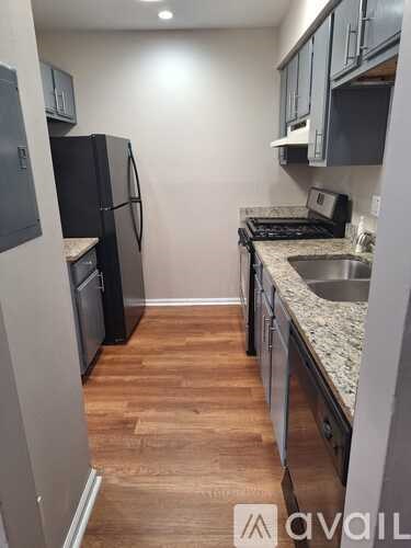 A kitchen with a black fridge and wooden floors.