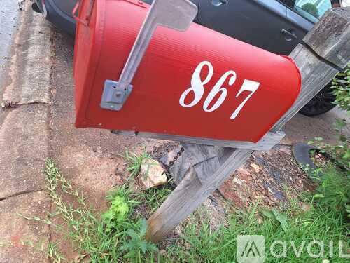 A red mailbox with the number 867 on it.