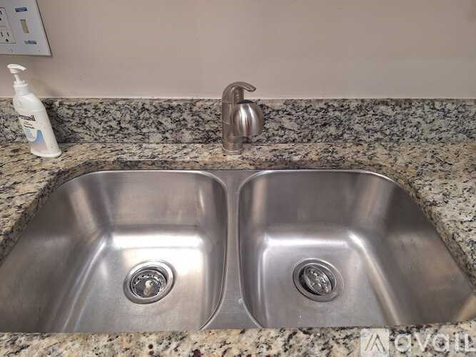 A silver sink with a soap dispenser and faucet.