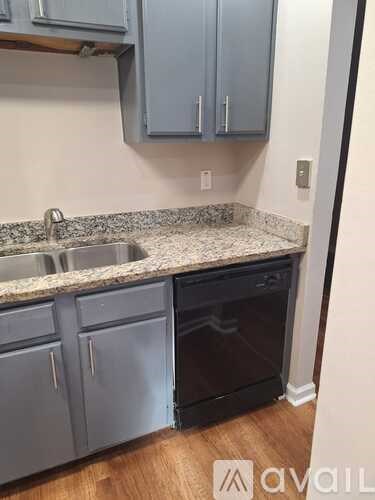 A kitchen with a granite countertop and grey cabinets.