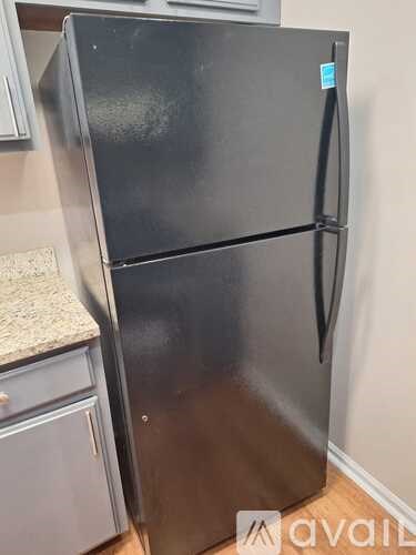 A black fridge with a blue tag on it.