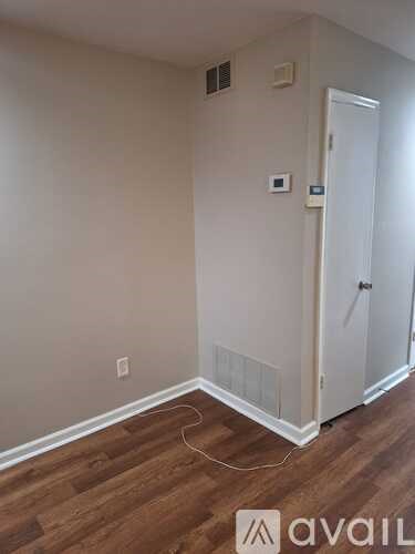 A room with a white door and wooden flooring.